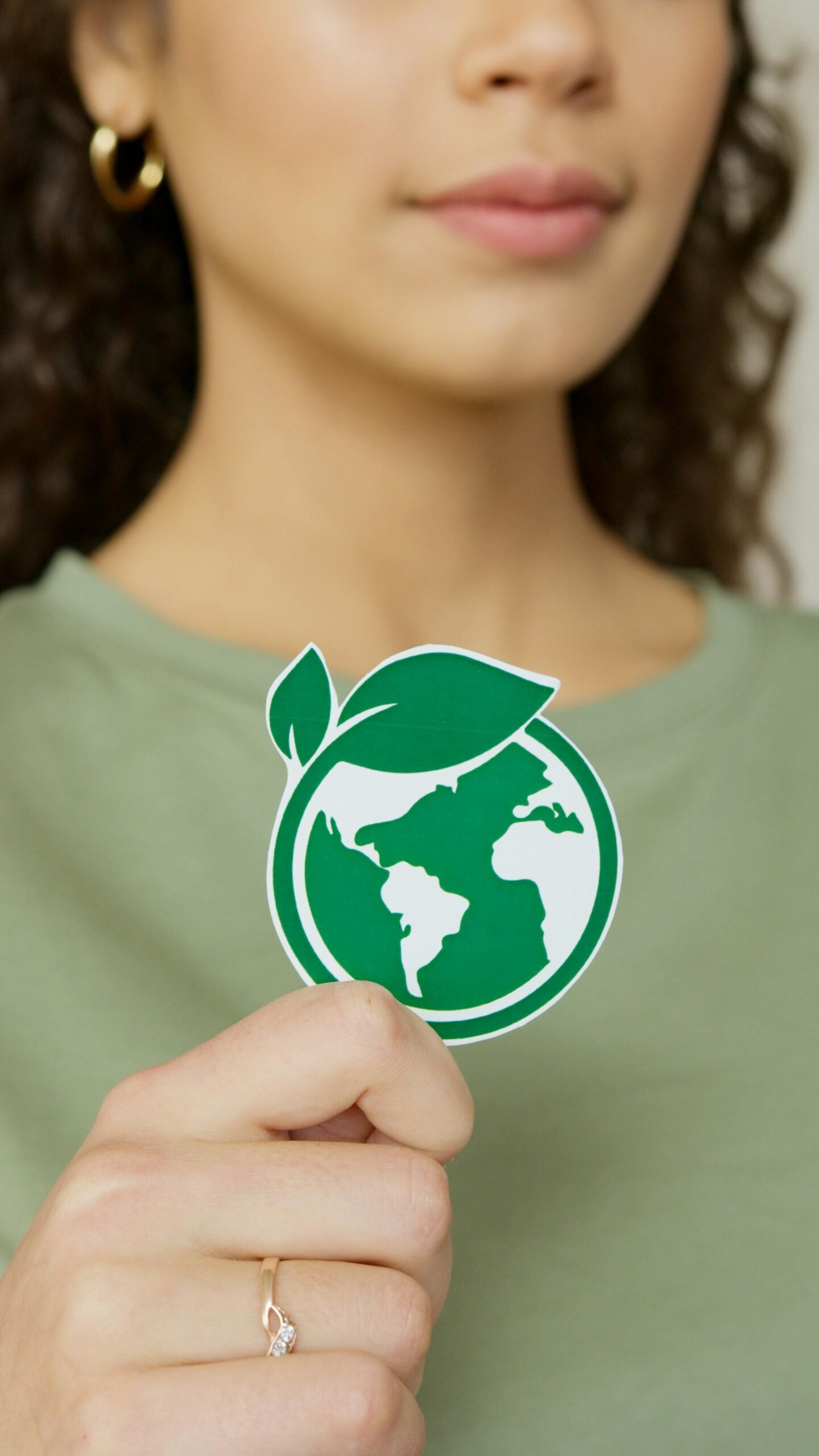 Close-up of a woman holding a green earth symbol, emphasizing environmental protection.
